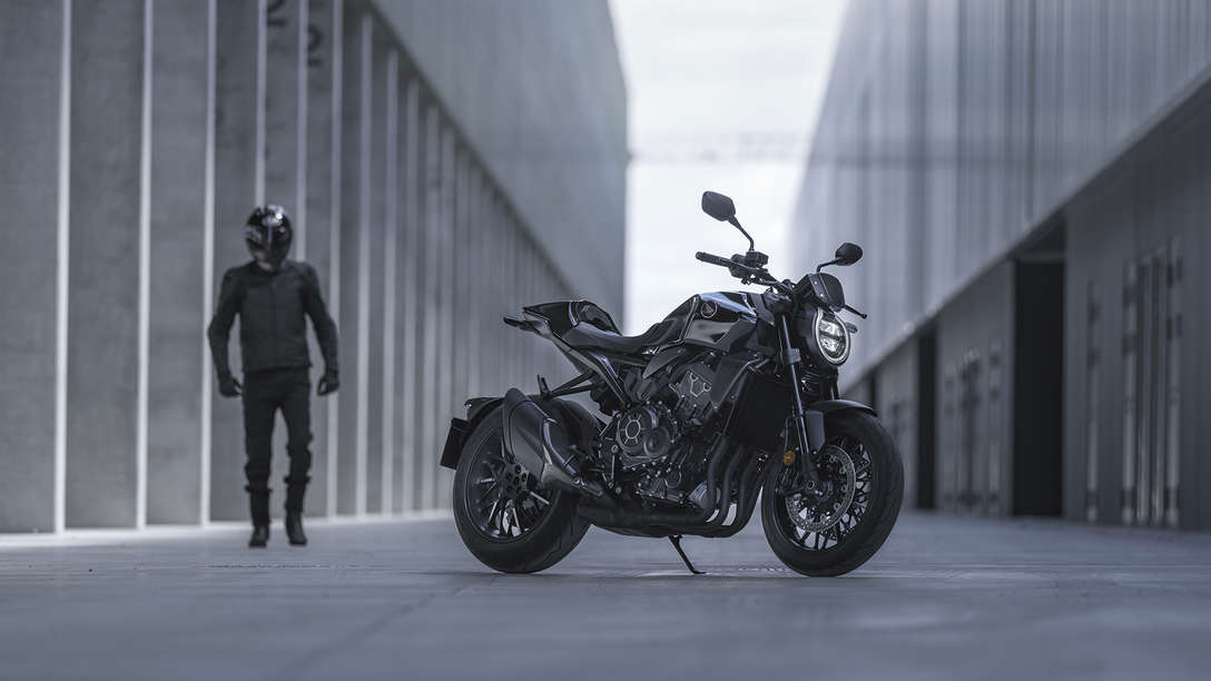 Honda CB1000R Black Edition – muž stojaci vedľa motocykla na ulici medzi budovami
